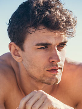Closeup of male model with brow hair, blue eyes and a stubble beard. Featuring cosmetic doctors facial threading