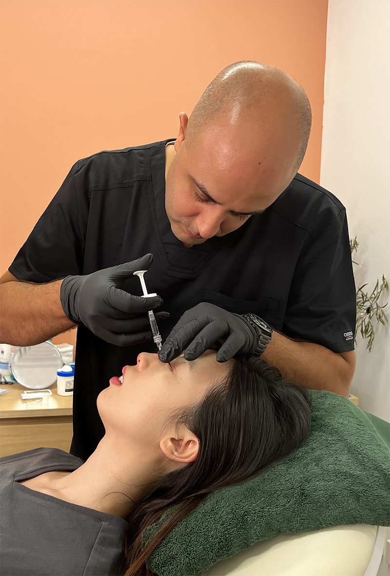 Nose filler being administered by Dr Tarek Shalabi in a female patient laying on bed