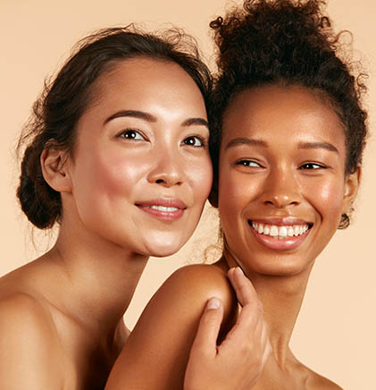 Closeup portrait of two female models with brown hair displaying cheerful expressions and beige background
